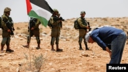 Israeli soldiers stand guard as a Palestinian man prays during a protest after the Israeli top court paved way for razing eight Palestinian hamlets, in Masafer Yatta, south of Hebron, in the Israeli-occupied West Bank, June 17, 2022.