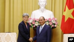 Australian Foreign Minister Penny Wong, left, and Vietnamese President Nguyen Xuan Phuc shake hands in Hanoi, Vietnam Monday June 27, 2022. (AP Photo/ Hoang Duong)