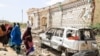Sejumlah perempuan berjalan di samping mobil dan rumah yang hancur akibat serangan yang dilakukan kelompok militan al-Shabab di Mogadishu, Somalia, pada 16 Februari 2022. (Foto: AFP/Hassan Ali Elmi)