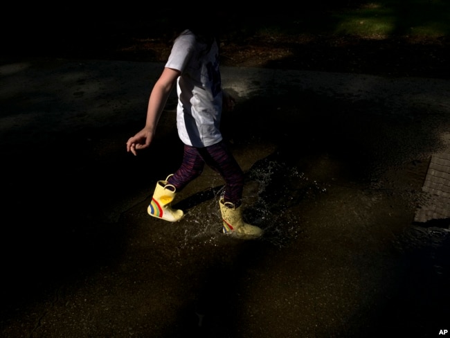 A child splashes in a puddle to beat the summer heat in Doraville, Ga. in this Wednesday, June, 15, 2022 iPhone photo, taken by Brynn Anderson. (AP Photo/Brynn Anderson)