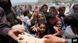 Afghans receive aid at a camp after an earthquake in Gayan district in Paktika province, June 26, 2022.