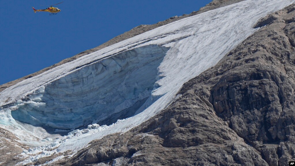 A rescue helicopter hovers over the Punta Rocca glacier near Canazei, in the Italian Alps in northern Italy, July 4, 2022, a day after a huge chunk of the glacier broke loose, sending an avalanche of ice, snow, and rocks onto hikers.