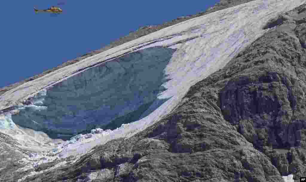 Sebuah helikopter penyelamat terbang di atas gletser Punta Rocca dekat Canazei, di Pegunungan Alpen Italia di Italia utara, sehari setelah sebagian besar gletser lepas, dan menjatuhkan longsoran es, salju, dan batu ke para pendaki. (Foto: AP)