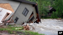 A house that was pulled into Rock Creek in Red Lodge, Mont., by raging floodwaters is seen Tuesday, June 14, 2022. (AP Photo/Matthew Brown)