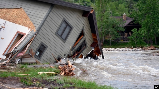 A house that was pulled into Rock Creek in Red Lodge, Mont., by raging floodwaters is seen Tuesday, June 14, 2022. (AP Photo/Matthew Brown)