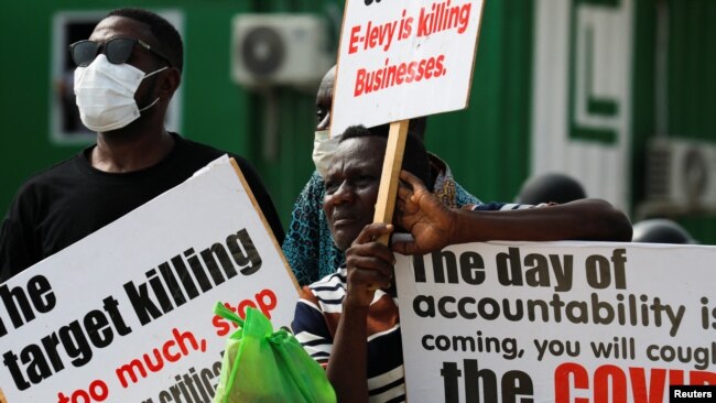 People hold signs as Ghanaians gather in the streets on the second day of protests over recent economic hardships, in Accra, Ghana, June 29, 2022.