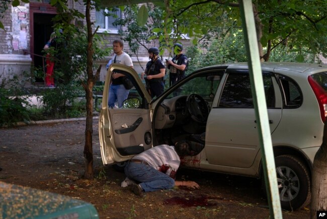 A dead body of a man killed by the Russian shelling lies by his car in city center in Slavyansk, Donetsk region, Ukraine, Monday, June 27, 2022. (AP Photo/Efrem Lukatsky)