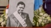 Un portrait du héros de l'indépendance congolais tué Patrice Lumumba près du cercueil contenant son seul reste, une dent, au Palais du Peuple à Kinshasa le 27 juin 2022. (Photo Arsène Mpiana / AFP)
