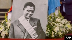 Un portrait du héros de l'indépendance congolais tué Patrice Lumumba près du cercueil contenant son seul reste, une dent, au Palais du Peuple à Kinshasa le 27 juin 2022. (Photo Arsène Mpiana / AFP)
