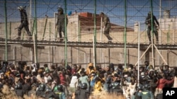 Riot police officers cordon off the area after migrants arrive on Spanish soil and crossing the fences separating the Spanish enclave of Melilla from Morocco in Melilla, Spain, June 24, 2022.