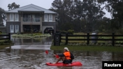 James Taylor paddles a kayak down a flooded residential street on his way to check on a friend's home, after rains inundated the area with floodwater in the McGraths Hill suburb of Sydney, Australia, on July 6, 2022. 