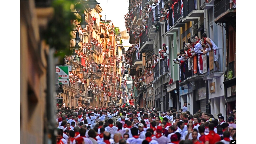 People run through the streets ahead of fighting bulls and steers during the first day of the running of the bulls at the San Fermin Festival in Pamplona, northern Spain, July 7, 2022.