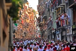People run through the streets ahead of fighting bulls and steers during the first day of the running of the bulls at the San Fermin Festival in Pamplona, northern Spain, July 7, 2022.