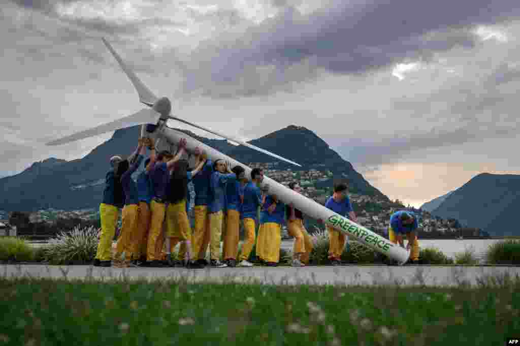 Greenpeace activists raise a factice wind turbine on the edge of Lake Lugano during a demonstration calling for a sustainable reconstruction of Ukraine, ahead of a two-day Ukraine Recovery Conference in Lugano, Switzerland.