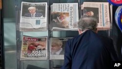 Seorang pelanggan memperhatikan berita halaman utama sejumlah koran yang dipajang di kios koran di London, Jumat, 8 Juli 2022. (Foto: Frank Augstein/AP Photo)