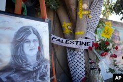 Pita kuning menandai lubang peluru di pohon dan potret di mana jurnalis Al-Jazeera Palestina-Amerika Shireen Abu Akleh terbunuh di Kota Jenin, Tepi Barat. (Foto: AP)