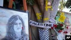 FILE: Yellow tape marks bullet holes on a tree and a portrait and flowers create a makeshift memorial, May 19, 2022, where Palestinian-American Al-Jazeera journalist Shireen Abu Akleh was killed in the West Bank city of Jenin.