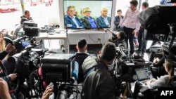 Periodistas cubren cómo líderes de las FARC enfrentan la justicia por primera vez bajo el nuevo sistema de justicia transicional posconflicto surgido de su acuerdo de paz con el gobierno, en la sede de la Jurisdicción Especial para la Paz (JEP) en Bogotá el 13 de julio de 2018. 