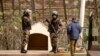 Des paramilitaires des Forces auxiliaires marocaines parlent avec un homme alors qu'ils montent la garde près de la barrière frontalière séparant le Maroc de l'enclave nord-africaine de Melilla en Espagne.