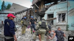 FILE - Search and rescue workers and local residents remove a body from under the rubble of a building after a Russian air raid in Lysychansk, Luhansk region, Ukraine, June 16, 2022.