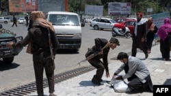 A Taliban fighter searches the belongings of a pedestrian along a blocked street ahead of a council meeting of tribal and religious leaders in Kabul, June 29, 2022.