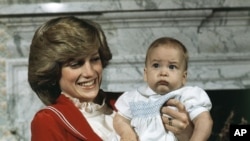 FILE - Britain's Prince William, the 6-month old son of Prince Charles and Princess Diana, with his mother during a photo call at Kensington Palace in London, England on Dec. 22, 1982. The world watched as Prince William grew from a towheaded schoolboy to