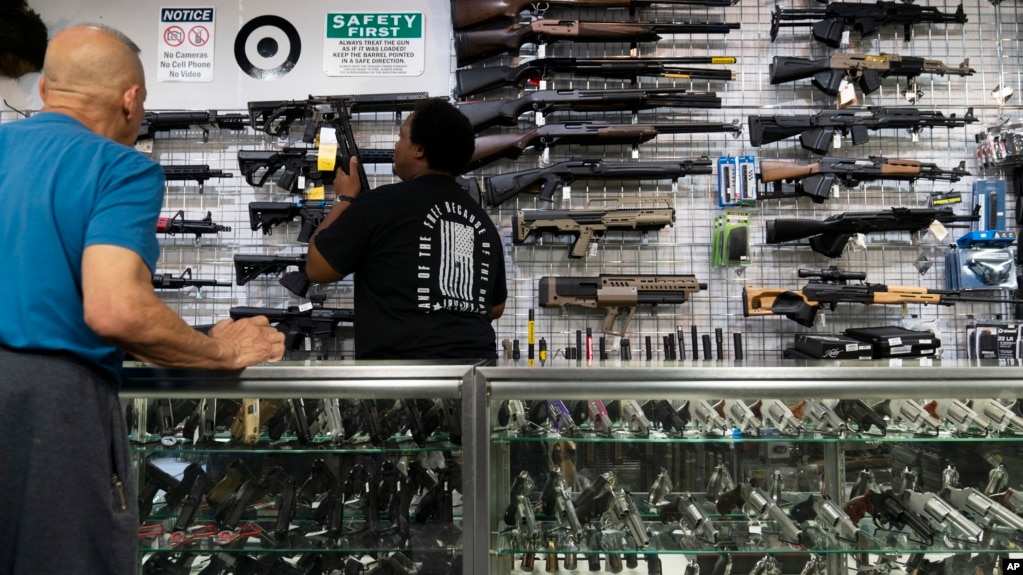 Sales associate Elsworth Andrews grabs a shotgun to show it to a customer at Burbank Ammo & Guns in Burbank, California, June 23, 2022. 