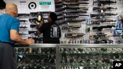 Sales associate Elsworth Andrews grabs a shotgun to show it to a customer at Burbank Ammo & Guns in Burbank, California, June 23, 2022. 