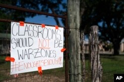 Sebuah tanda setelah kasus penembakan yang menewaskan belasan siswa digantung di pagar dekat Sekolah Dasar Robb di Uvalde, Texas, Jumat, 3 Juni 2022. (Foto: AP/Jae C. Hong)