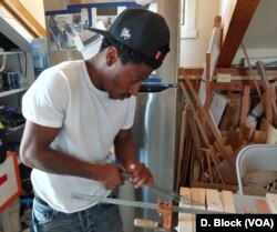 FILE - Apprentice Tykeece Simms uses his new carpentry skills to cut wood to make a doghouse. (Deborah Block/VOA)