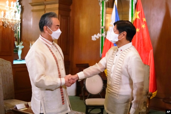 In this photo provided by the Malacanang Presidential Photographers Division, Philippine President Ferdinand Marcos Jr., right, greets Chinese Foreign Minister Wang Yi as the arrives for a courtesy call at the Malacanang Presidential Palace in Manila, Philippines on Wednesday, July 6, 2022. (Malacanang Presidential Photographers Division via AP)