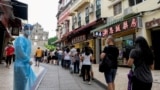 FILE - People queue for COVID-19 testing in Macau, China, June 20, 2022. Testing for all residents will take place three times this week across the city, with people also required to take rapid antigen tests in between. 