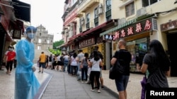 FILE - People queue for COVID-19 testing in Macau, China, June 20, 2022. Testing for all residents will take place three times this week across the city, with people also required to take rapid antigen tests in between. 