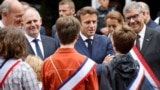 Presidente francês Emmanuel Macron (centro) fala com adolescentes ao chegar à assembleia de voto em Le Touquet, para votar, Paris, 19 Junho 2022