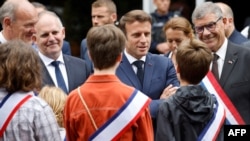 France's President Emmanuel Macron (C) speaks to children while officials including Pas-de-Calais' deputy Robert Therry (R) look on as he arrives to vote in the second stage of French parliamentary elections at a polling station in Le Touquet, June 19, 20
