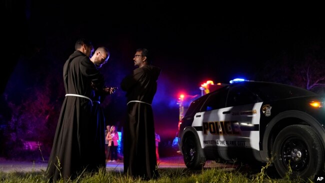 Sacerdotes se reúnen cerca del lugar donde las autoridades dicen que decenas de personas fueron encontradas muertas y muchas otras fueron llevadas a hospitales con enfermedades relacionadas con el calor después de que se encontró un semirremolque que contenía a presuntos migrantes, el lunes 27 de junio de 2022, en San Antonio. (Foto AP/Eric Gay)