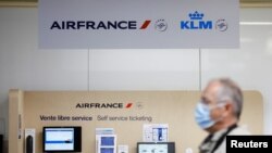 A passenger, wearing a protective face mask, walks past a self service ticketing of airline company Air France in the departures area at the Nantes-Atlantique airport in Bouguenais near Nantes, France, June 29, 2022. 