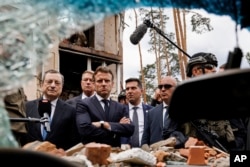 Italian Prime Minister Mario Draghi, left, and French President Emmanuel Macron watch debris as they visit Irpin, outside Kyiv, Thursday, June 16, 2022. (Ludovic Marin, Pool via AP)