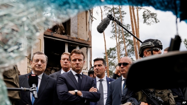 Italian Prime Minister Mario Draghi, left, and French President Emmanuel Macron watch debris as they visit Irpin, outside Kyiv, Thursday, June 16, 2022.