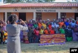 Anchia Camal Mulima, koordinator center “Lemusica” (Bangunlah wanita dan ikuti jalanmu), foto bersama warga perempuan dari Mahnene setelah sesi pencegahan dan kesadaran untuk kekerasan terhadap perempuan, di depan fasilitas penampungan dan rumah bantuan masyarakat di Provinsi Manica, Mozambik pada 18 Mei 2022. (Foto: Alfredo Zuniga / AFP)
