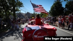 ILLUSTRATION - Une femme brandit le drapeau américain lors du défilé annuel du 4 juillet à Barnstable Village, à Cape Cod, Massachusetts, États-Unis, le 4 juillet 2022. 