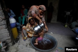 Rehmat, 30, membantu Razia, 25, memandikan putrinya yang berusia enam bulan, Tamanna, untuk mendinginkan tubuh saat gelombang panas, di Jacobabad, Pakistan, 15 Mei 2022. (REUTERS/Akhtar Soomro)