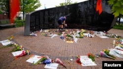 FILE - A man leaves flowers at a memorial site after a mass shooting at a Fourth of July parade in the Chicago suburb of Highland Park, Illinois, July 6, 2022.