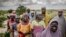 A group of women wait for the arrival of a United Nations convoy near the village of Sabon Machi, Maradi region, Niger on Aug. 16, 2018. 