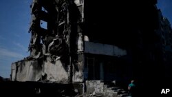 A woman walks past a building destroyed in Russian shelling in Borodyanka, on the outskirts of Kyiv, Ukraine, June 21, 2022.