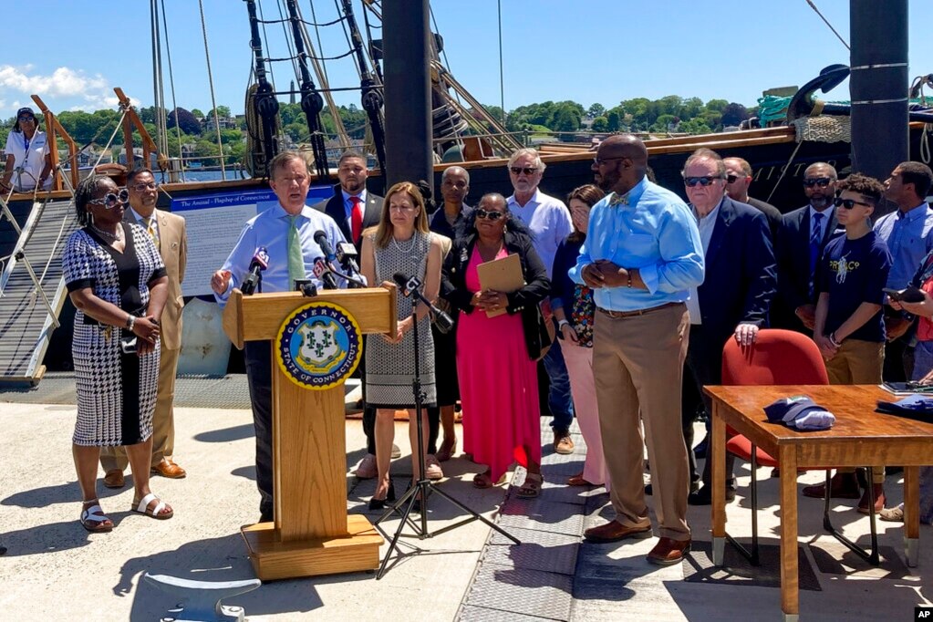 康涅狄格州长拉曼特在康州新伦敦一艘复制的“阿米斯塔德”号运奴船前举行的仪式上签署将6月19日六月节定为州假日的法案。(2022年6月10日)(photo:VOA)