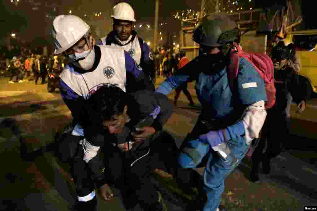 Un hombre es ayudado por personal médico de emergencia después de ser alcanzado por los gases lacrimógenos disparados por las fuerzas de seguridad.