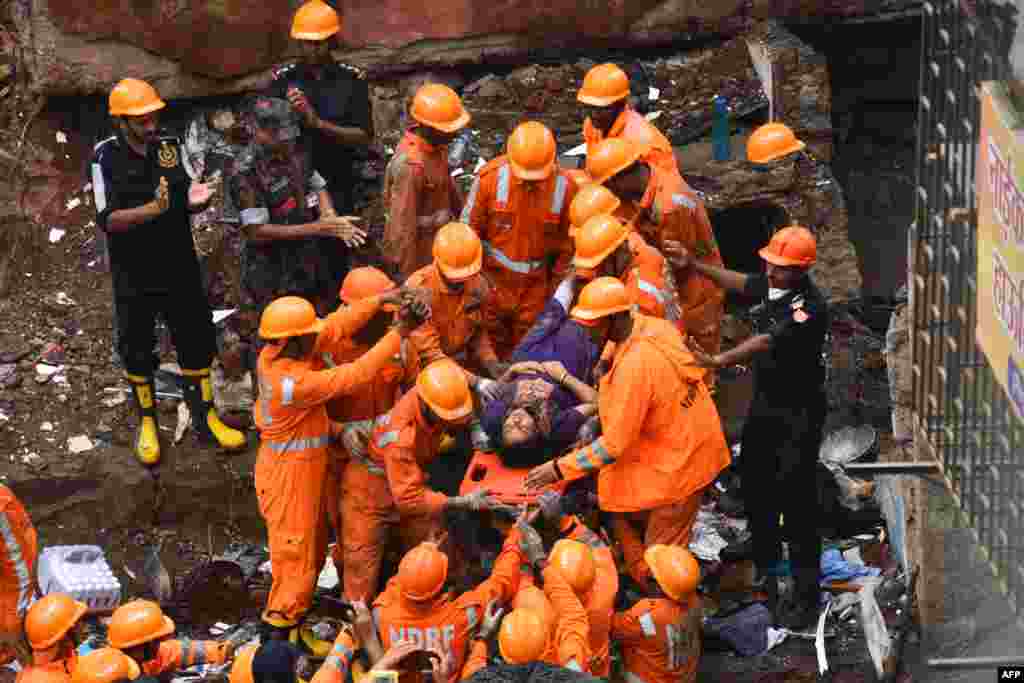Rescue workers cheer as a survivor is brought out alive on a stretcher from the debris of a collapsed building in Mumbai, India.