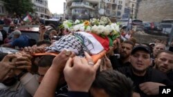 FILE - Palestinian mourners carry the body of veteran Palestinian-American reporter Shireen Abu Akleh out of the office of Al Jazeera in the West Bank city of Ramallah, May 11, 2022.