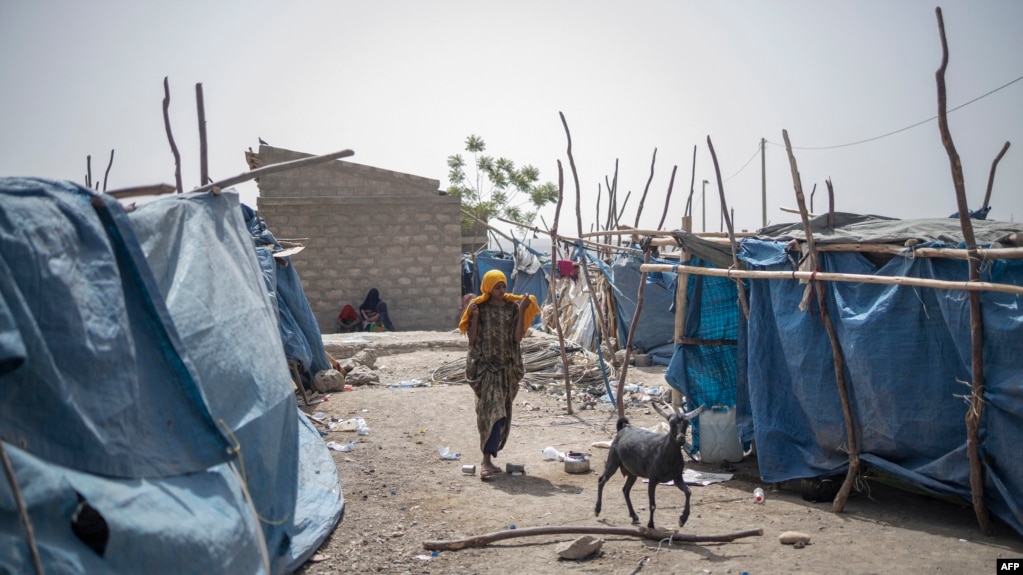 FILE - A woman walks between tents at the internally displaced persons camp of Guyah, Afar region, Ethiopia, May 17, 2022.